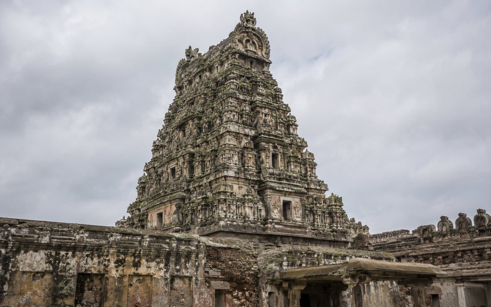 Temple gopuram in disrepair — weathered stonework with moss growth